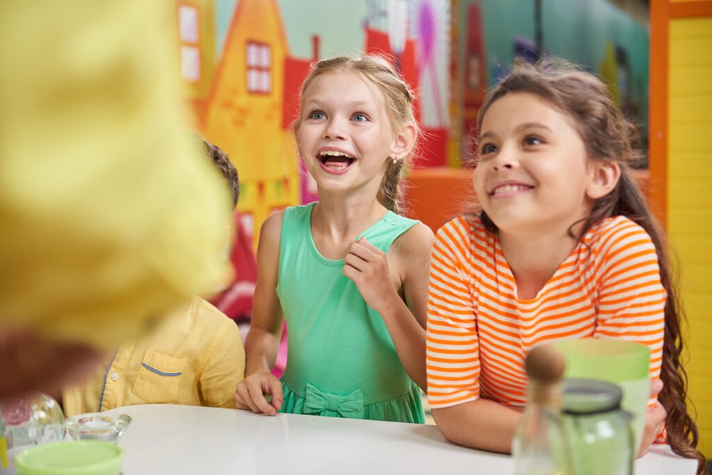 DOC Kinderbetreuung Kinder in der DOC-Kinderbetreuung. 2 Mädchen lachen und schauen die Betreuer an.